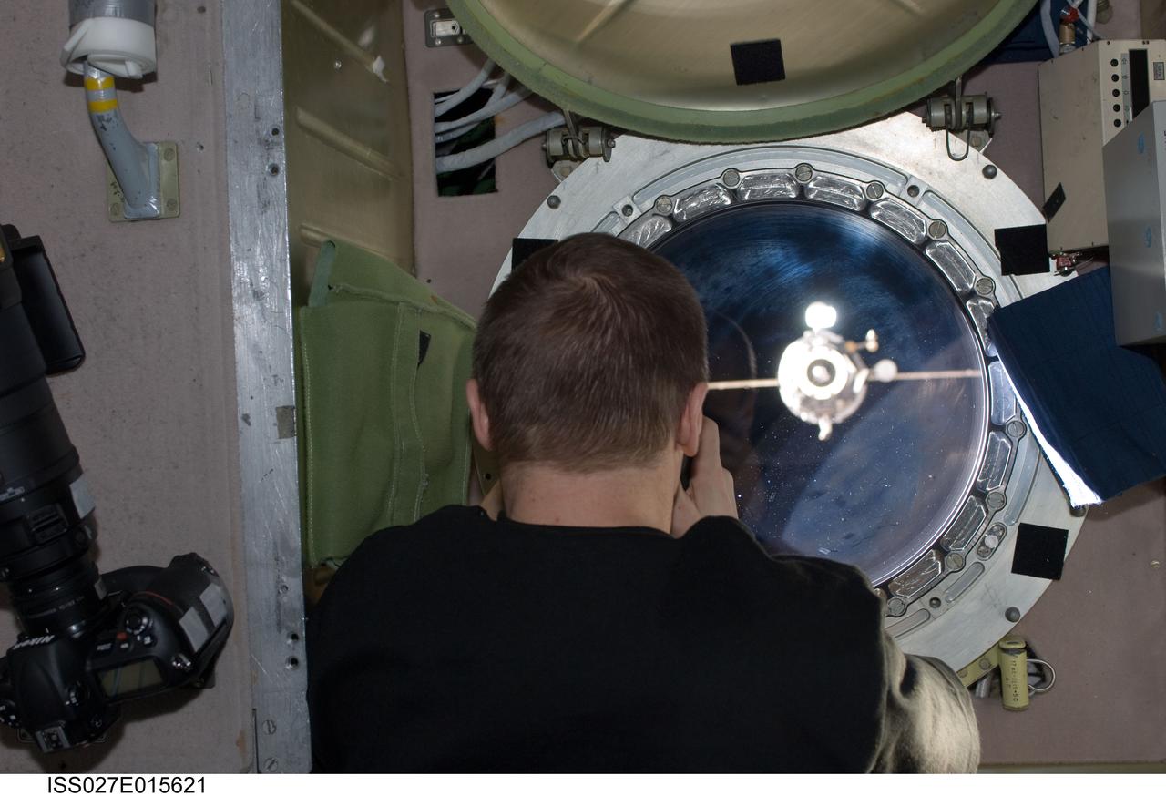 ISS027-E-015621 (22 April 2011) --- Russian cosmonaut Dmitry Kondratyev, Expedition 27 commander, photographs the departure of the unpiloted ISS Progress 41 supply vehicle through a window in the Zvezda Service Module of the International Space Station.