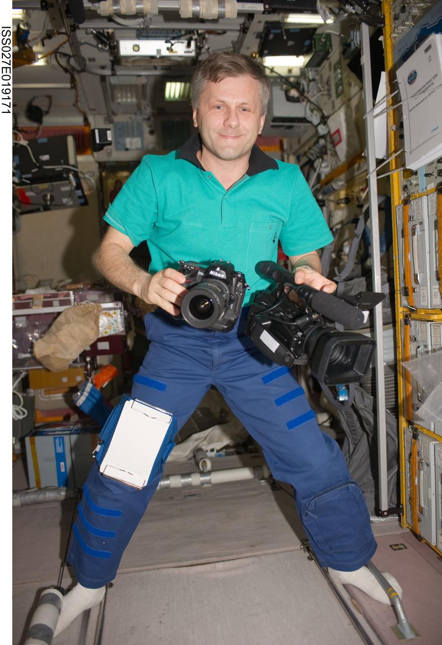 ISS027-E-019171 (29 April 2011) --- Russian cosmonaut Andrey Borisenko, Expedition 27 flight engineer, is pictured while holding cameras in the Zvezda Service Module of the International Space Station.