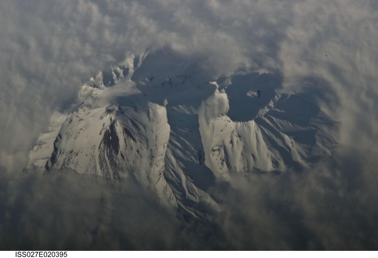 ISS027-E-020395 (2 May 2011) --- Avachinsky Volcano, Kamchatka Peninsula, Russia is featured in this image photographed by an Expedition 27 crew member on the International Space Station. The Kamchatka Peninsula, located along the Pacific ?ring of fire?, includes more than 100 identified volcanoes. While most of these volcanoes are not actively erupting, many are considered to be dangerous due to their past eruptive history and proximity to population centers and air travel corridors. This detailed photograph highlights the summit crater and snow-covered upper slopes of the Avachinsky stratovolcano exposed above a surrounding cloud deck. The 2,741-meter-high Avachinsky volcano has an extensive historical and geological record of eruptions with the latest activity observed in 2008. The large city of Petropavlovsk, Kamchatka is located approximately 25 kilometers to the southwest and, according to scientists, is built over approximately 30,000 ? 40,000 year old debris avalanche deposits that originated from Avachinsky ? suggesting that the city may be at risk from a similar hazard in the future. To the southeast (right), the large breached crater of Kozelsky Volcano is also visible above the clouds. Kozelsky is a parasitic cone, formed by the eruption of material from vents along the flank of Avachinsky volcano. The topography of the volcanoes is accentuated by shadows produced by the relatively low sun angle, and by the oblique viewing angle. Oblique images are taken looking outwards at an angle from the International Space Station, rather than the ?straight down? (or nadir) view typical of most orbital Earth-observing sensor systems.