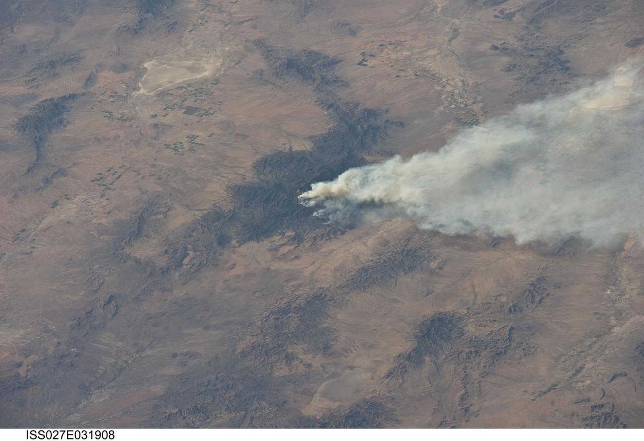 ISS027-E-031908 (15 May 2011) --- The Horseshoe 2 fire is featured in this image photographed by an Expedition 27 crew member on the International Space Station. The Horseshoe 2 fire, located along the southeastern flank of the Chiricahua Mountains in southeastern Arizona, began on May 8, 2011 at approximately 11:00 a.m. The fire is thought to have been started by human activities. This photograph illustrates the area (approximately 8,900 hectares, or 22,110 acres) and position of the fire within the mountains on May 15, 2011, as well as an extensive smoke plume extending to the east-northeast over a distance of at least 60 kilometers (approximately 40 miles).  As of May 19, 2011, the fire had burned an area of nearly 14,000 hectares (approximately 34,400 acres) of grasses, shrubs, and trees along the mountain slopes. The Chiricahua Mountains are included within the Chiricahua National Monument located near the borders of Arizona, USA; New Mexico, USA; and Chihuahua, United Mexican States. Elevations in the mountains range from approximately 914 – 3,267 meters (300 – 10,720 feet) above sea level. The higher elevations—known regionally as “sky islands”—allow for biologically diverse plant and animal communities, adapted to cooler and wetter conditions, to survive while surrounded by semi-arid to arid desert conditions at lower elevations. The image highlights this contrast in environments; pine and oak forest contributes to the dark coloration of the upper slopes and peaks of the Chiricahuas at center, while the flat, gray to tan surface of Willcox Playa (an interior-draining basin or dry lake) to the northwest is indicative of the adjacent desert environment.
