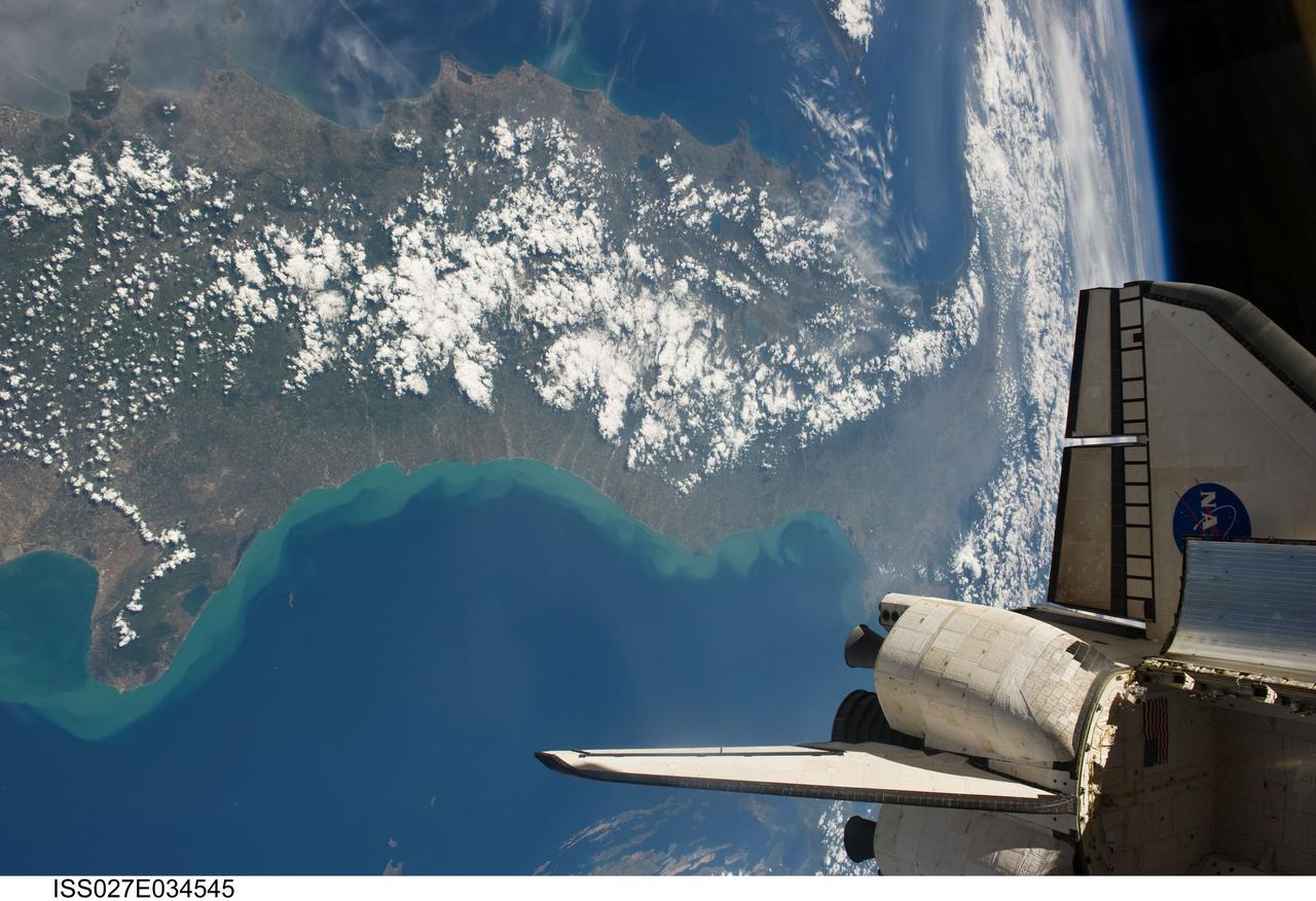 ISS027-E-034545(19 May 2011) --- Backdropped against a scene showing part of Italy, this image featuring an aft section of the space shuttle Endeavour in the foreground was photographed by an Expedition 27 crew member aboard the International Space Station while the two spacecraft were docked. The vertical stabilizer, the orbital maneuvering system (OMS) pods and the lower part of the port wing are seen. Twelve astronauts and cosmonauts were busy aboard the joint complex, moving hardware and preparing for a May 20 space walk.