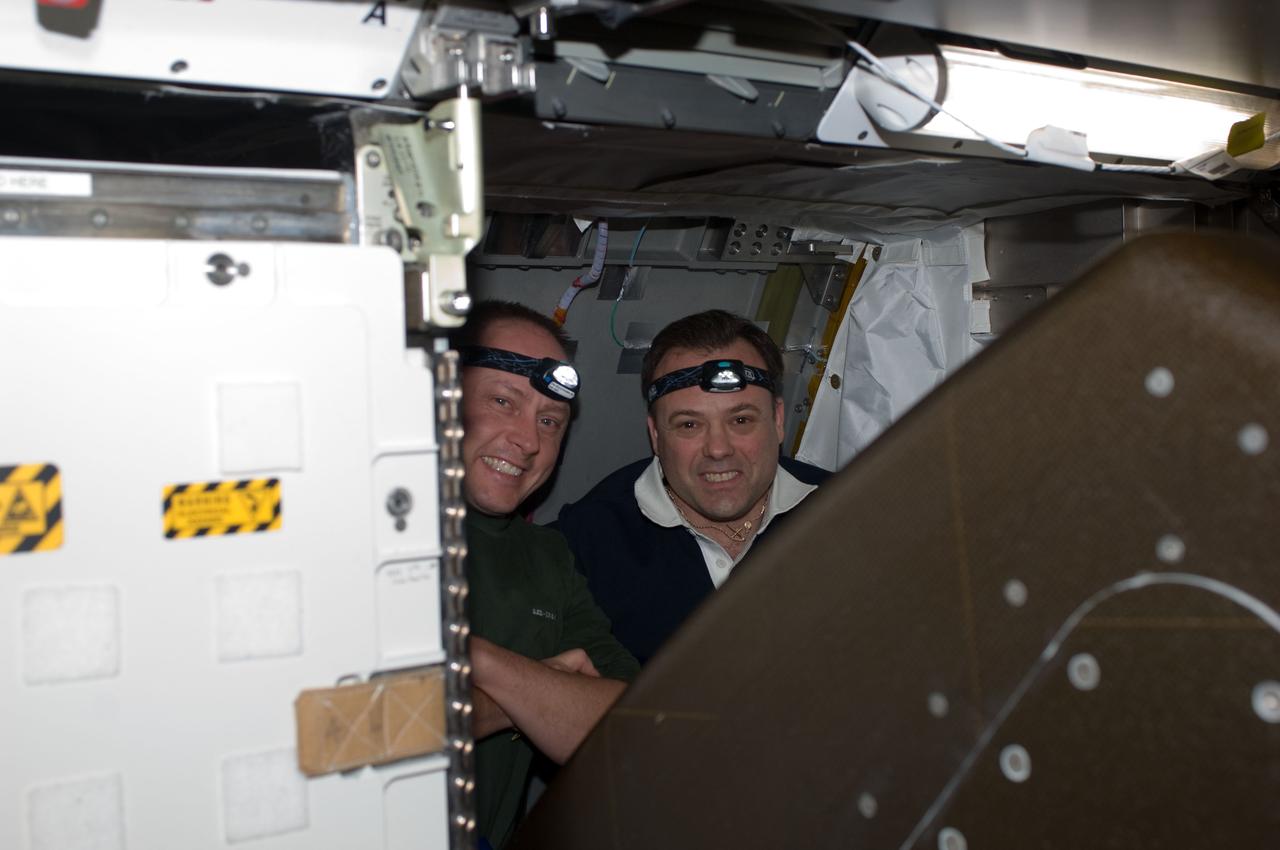 ISS028-E-005116 (24 May 2011) --- NASA astronauts Michael Fincke (left), STS-134 mission specialist; and Ron Garan, Expedition 28 flight engineer, are pictured while working behind a rack on the International Space Station while space shuttle Endeavour remains docked with the station.