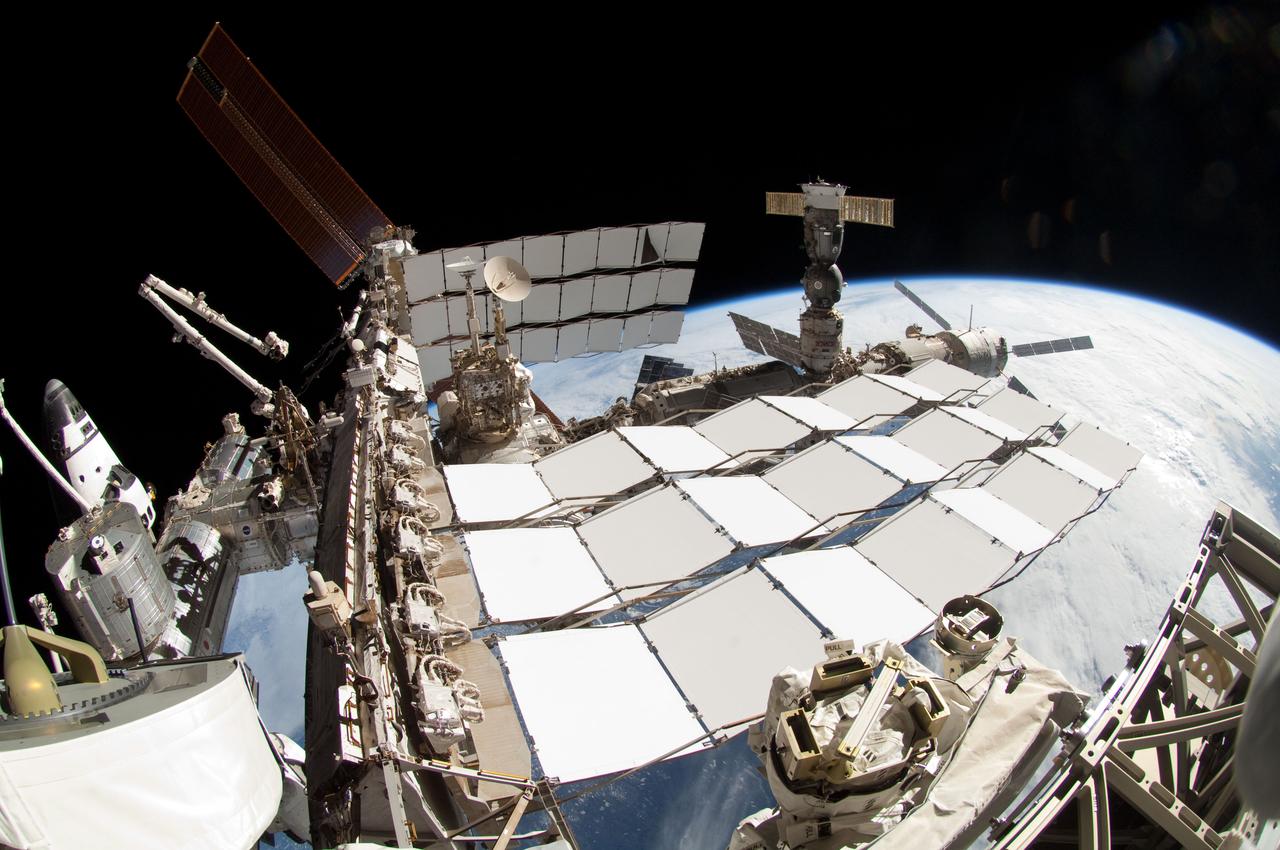 ISS028-E-005676 (27 May 2011) --- A portion of the International Space Station and the docked space shuttle Endeavour (left) are featured in this image photographed by a spacewalker, using a fish-eye lens attached to an electronic still camera, during the STS-134 mission?s fourth session of extravehicular activity (EVA). Earth?s horizon and the blackness of space provide the backdrop for the scene.