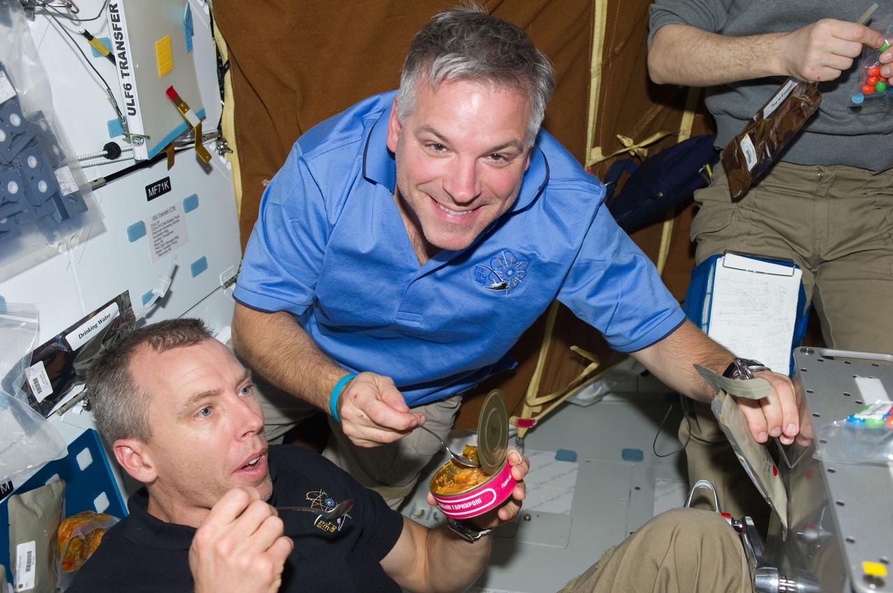 ISS028-E-005912 (27 May 2011) --- NASA astronauts Greg H. Johnson (top), STS-134 pilot; and Andrew Feustel, mission specialist, share a meal with their shuttle and station crewmates on the middeck of space shuttle Endeavour while docked with the International Space Station.
