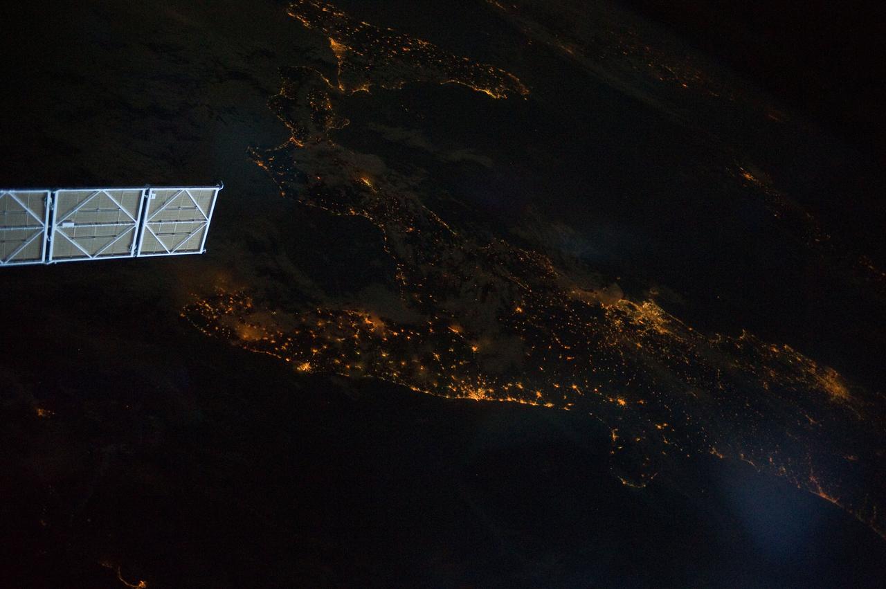 ISS028-E-008604 (11 June 2011) --- A night view of the southern Italian Peninsula is featured in this image photographed by an Expedition 28 crew member on the International Space Station. The Earth’s surface at night is covered with a delicate tracery of lights, particularly in regions – such as Europe – that have a long history of urban development. Large urban areas are recognizable from orbit due to extensive electric lighting and distinct street patterns; with smaller urban areas spread across the land surface and coastlines, the outlines of continental landmasses are easily discernable at night. This photograph highlights the night time appearance of the southern Italian Peninsula; the toe and heel of Italy’s “boot” are clearly defined by the lights of large cities such as Naples, Bari, and Brindisi as well as numerous smaller urban areas. The bordering Adriatic, Tyrrhenian, and Ionian Seas appear as dark regions to the east, west, and south of the boot. The city lights of Palermo and Catania on the island of Sicily are visible at image bottom center. The space station was located over an area of Romania close to the capital city of Bucharest – approximately 945 kilometers to the northeast—at the time this image was taken. Part of a docked Russian spacecraft solar panel array is visible in the foreground at left. The distance between the image subject area and the position of the photographer, as well as the viewing angle looking outwards from the space station, contributes to the distorted appearance of the Italian Peninsula and Sicily in the image.