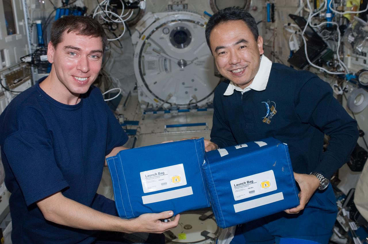 ISS028-E-009410 (24 June 2011) --- Russian cosmonaut Sergei Volkov (left) and Japan Aerospace Exploration Agency astronaut Satoshi Furukawa, both Expedition 28 flight engineers, pose for a photo while holding stowage bags in the Kibo laboratory of the International Space Station.