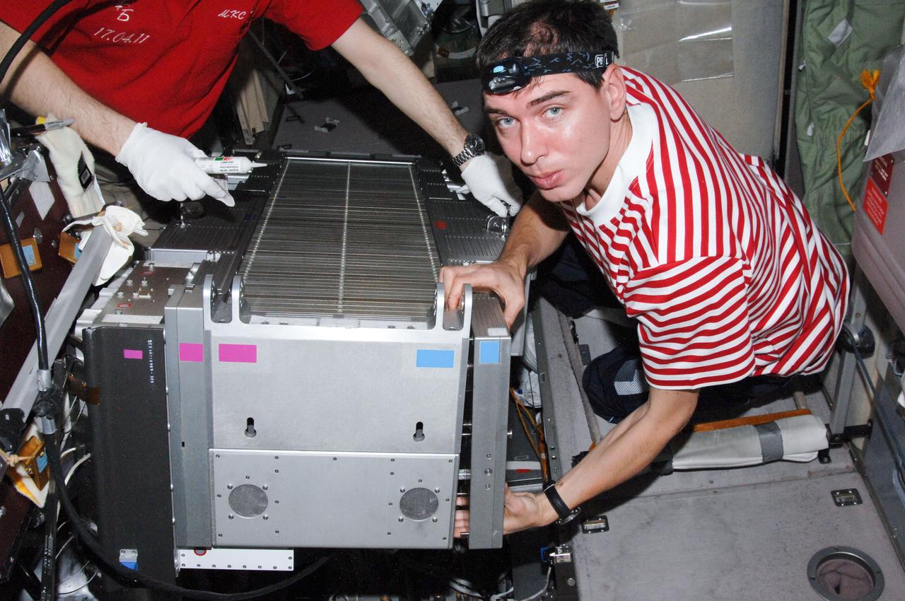 ISS028-E-013758 (1 July 2011) --- Russian cosmonauts Sergei Volkov, Expedition 28 flight engineer; and Andrey Borisenko (mostly out of frame at left), commander, perform in-flight maintenance on the Treadmill Vibration Isolation System (TVIS) in the Zvezda Service Module of the International Space Station.