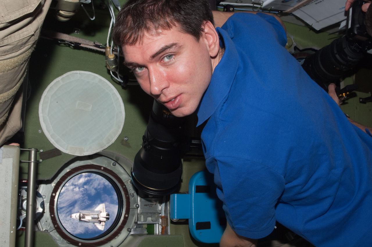ISS028-E-015794 (10 July 2011) --- Russian cosmonaut Sergei Volkov, Expedition 28 flight engineer, has picked out a window on the Zvezda service module from which to view and photograph the space shuttle Atlantis, which can be seen here as a tiny object, during rendezvous operations on July 12, 2011.