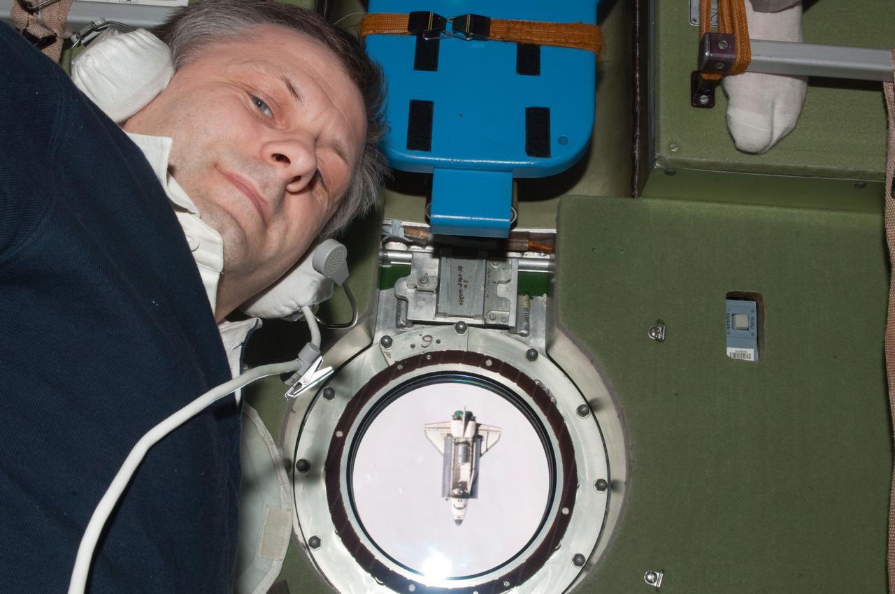 ISS028-E-015798 (10 July 2011) --- Russian cosmonaut Andrey Borisenko, Expedition 28 commander, has picked out a window on the Zvezda service module from which to view and photograph the space shuttle Atlantis, which can be seen here as a tiny object, during rendezvous operations on July 12, 2011.