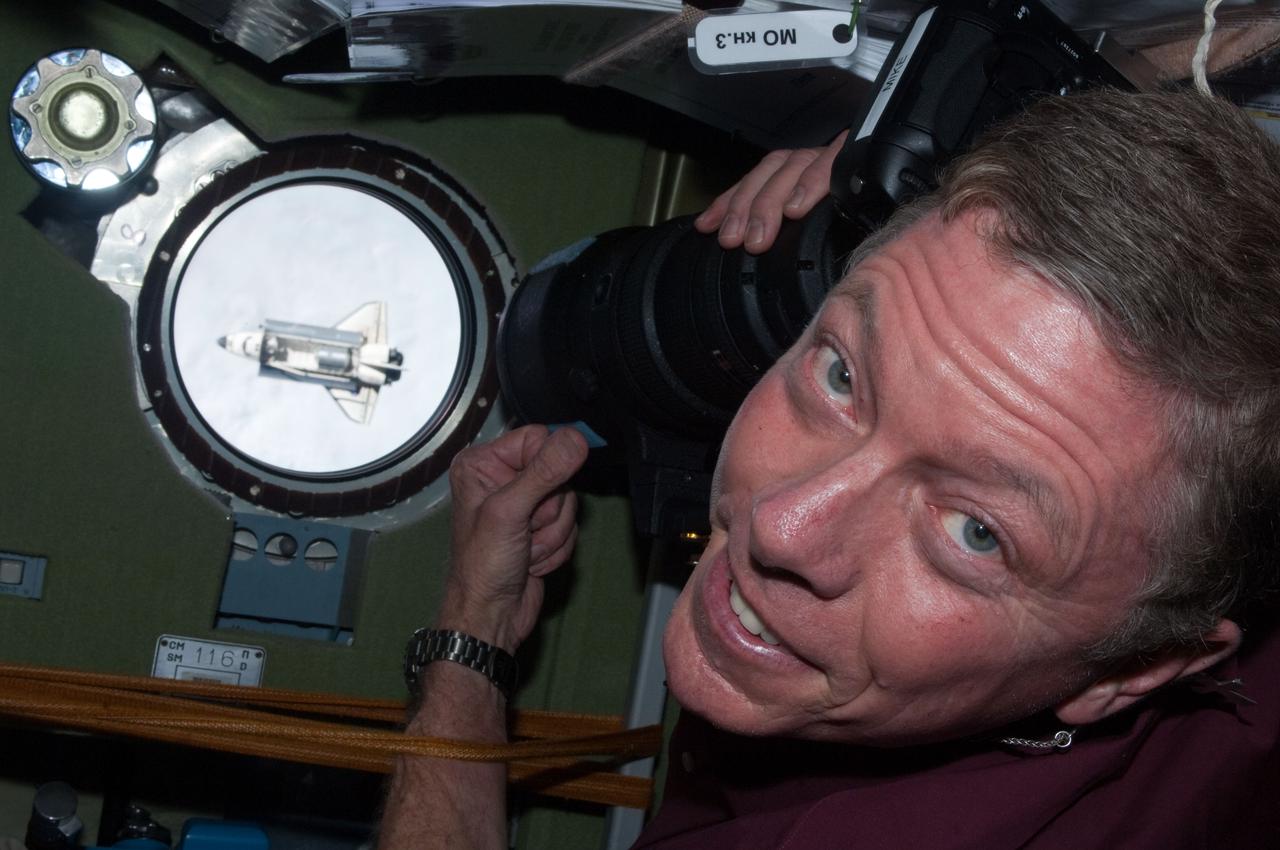 ISS028-E-015799 (10 July 2011) --- NASA astronaut Mike Fossum, Expedition 28 flight engineer, has picked out a window on the Zvezda service module from which to view and photograph the space shuttle Atlantis, which can be seen here as a tiny object during rendezvous operations on July 12, 2011.
