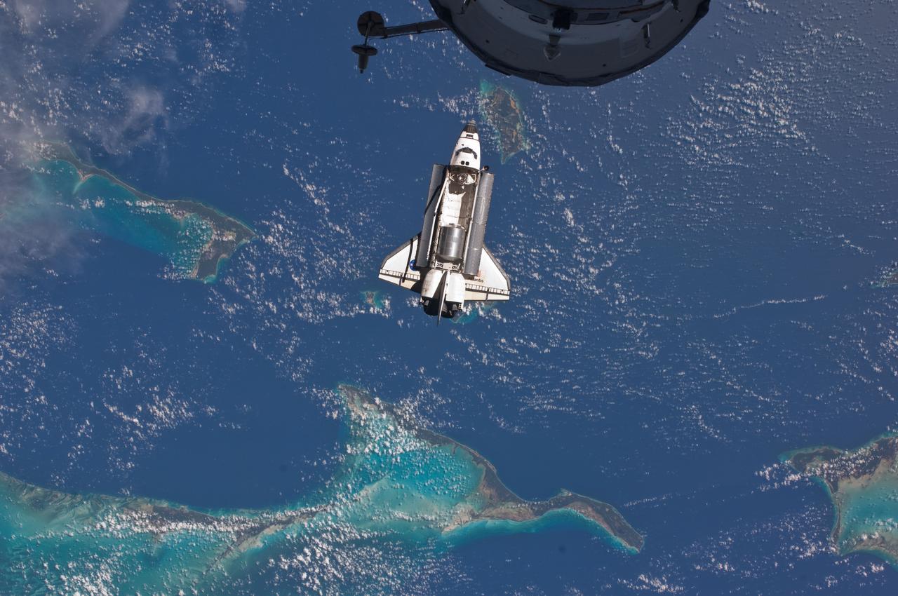 ISS028-E-015818 (10 July 2011) --- The space shuttle Atlantis is seen over the Bahamas prior to a perfect docking with the International Space Station at 10:07 a.m. (CDT).  Part of a Russian Progress spacecraft which is docked to the station is in the foreground.