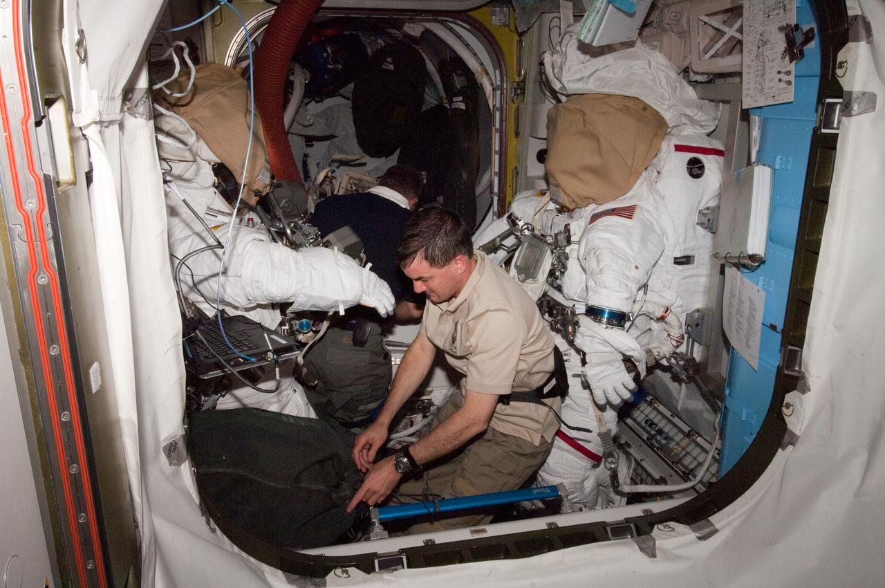 ISS028-E-015888 (10 July 2011) --- In the Quest airlock of the International Space Station, NASA astronaut Rex Walheim, STS-135 mission specialist, checks out the extravehicular mobility unit space suits designated for duty on a spacewalk less than 48 hours away. Expedition 28 crewmembers Mike Fossum (right suit) and Ron Garan will be inside the suits for the spacewalk, scheduled for the morning of July 12.