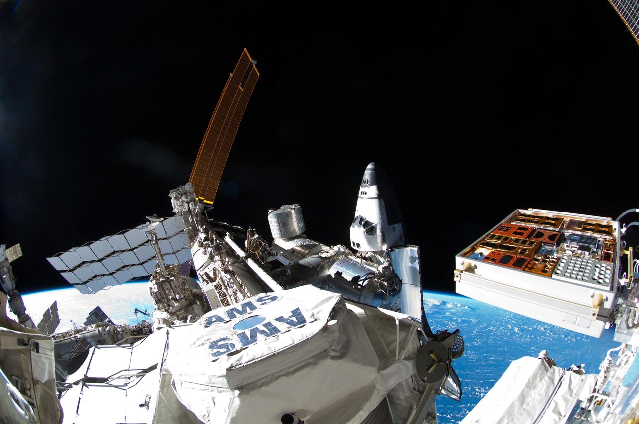 ISS028-E-016128 (12 July 2011) --- This picture, photographed by NASA astronaut Ron Garan during the spacewalk conducted on July 12, 2011, shows the International Space Station with space shuttle Atlantis docked at center frame and a Russian Soyuz docked to Pirs, at left. In the center foreground is the Alpha Magnetic Spectrometer (AMS) experiment installed during the STS-134 mission. AMS is a state-of-the-art particle physics detector designed to use the unique environment of space to advance knowledge of the universe and lead to the understanding of the universe's origin by searching for antimatter and dark matter, and measuring cosmic rays.