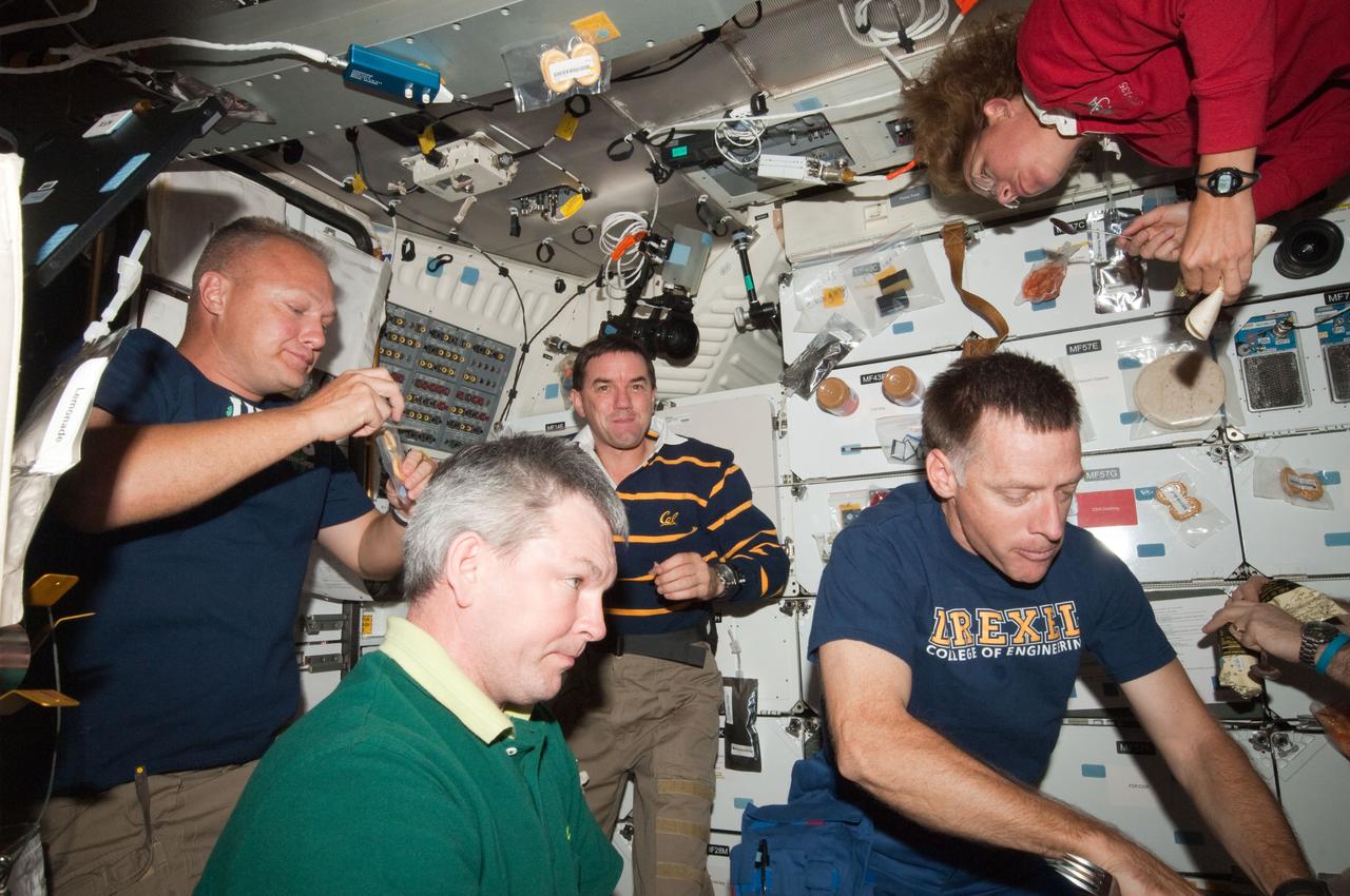 ISS028-E-016601 (14 July 2011) --- The four STS-135 crewmembers, quite accustomed to going en masse to the International Space Station, reverse roles for the occasion of the "All-American Meal" on the middeck of the space shuttle Atlantis. Russian cosmonaut Alexander Samokutyaev, Expedition 28 flight engineer, shares the meal the Atlantis crew in the frame and with five of his station crewmates, who are out of frame. The STS-135 crewmembers are NASA astronauts Chris Ferguson (right), mission commander, along with Doug Hurley (left), pilot; and Sandy Magnus and Rex Walheim, both mission specialists.