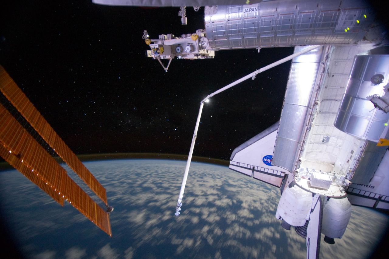 ISS028-E-016952 (14 July 2011) --- One of the members of the joint crews for STS-135 and International Space Station Expedition 28 exposed this image of Atlantis and its robot arm over Earth's horizon and its faint thin line of airglow, a station solar array panel and the Japanese Experiment Module Exposed Facility (JEF).