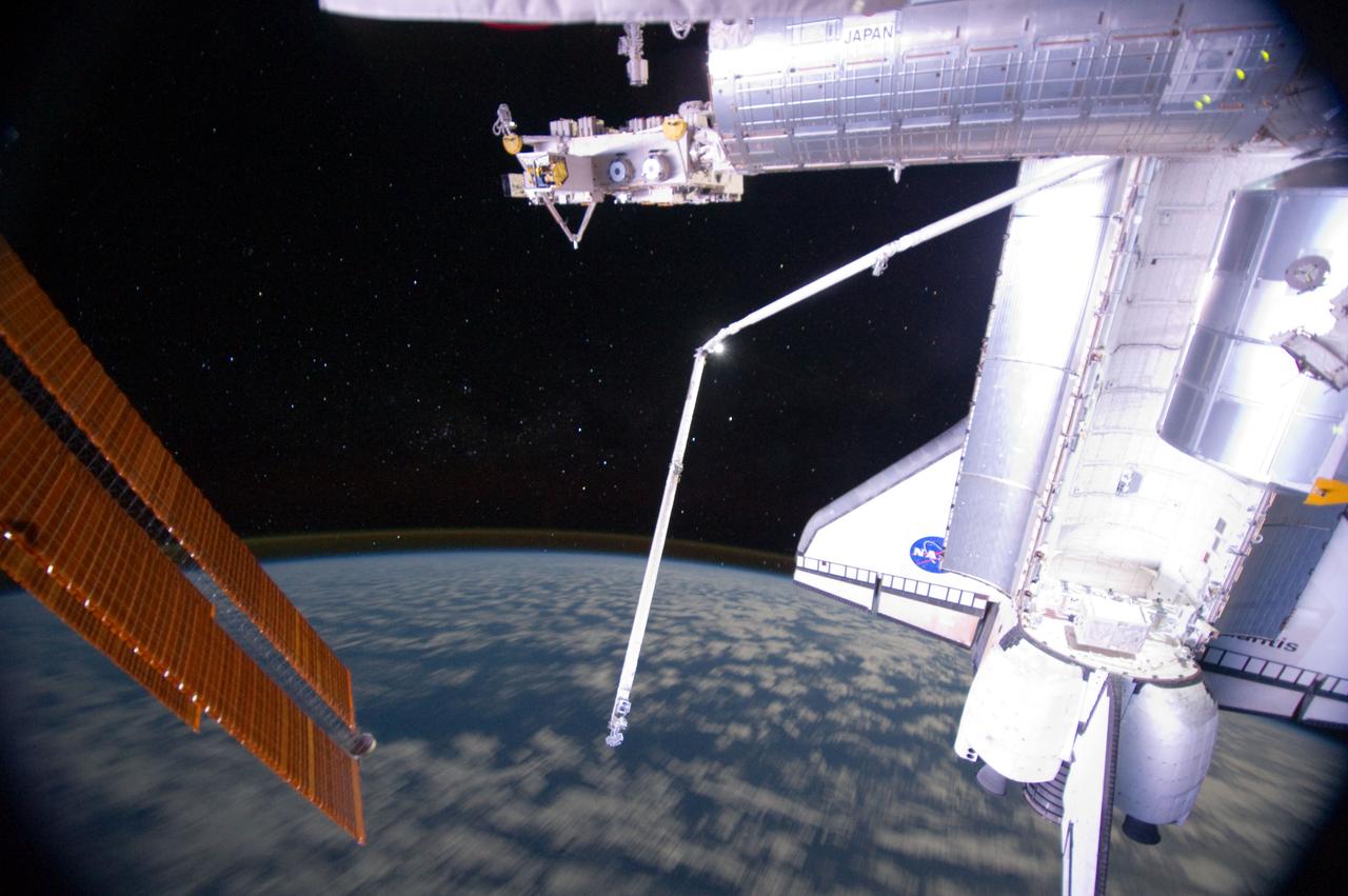 ISS028-E-016955 (14 July 2011) --- One of the members of the joint crews for STS-135 and International Space Station Expedition 28 exposed this image of Atlantis and its robot arm over Earth's horizon and its faint thin line of airglow, a station solar array panel and the Japanese Experiment Module Exposed Facility (JEF).