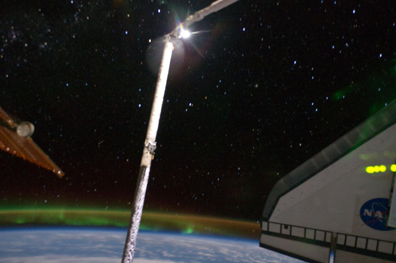 ISS028-E-017393 (17 July 2011) --- This is one of a series of photographs recorded from the International Space Station showing the docked space shuttle Atlantis' port side wing backdropped against the blackness of space. At the bottom of the frame can be seen airglow over Earth, intermingled with auroral activity. A solar wing connected to the station and part of the Orbiter Boom Sensor System are on the left side of the frame.