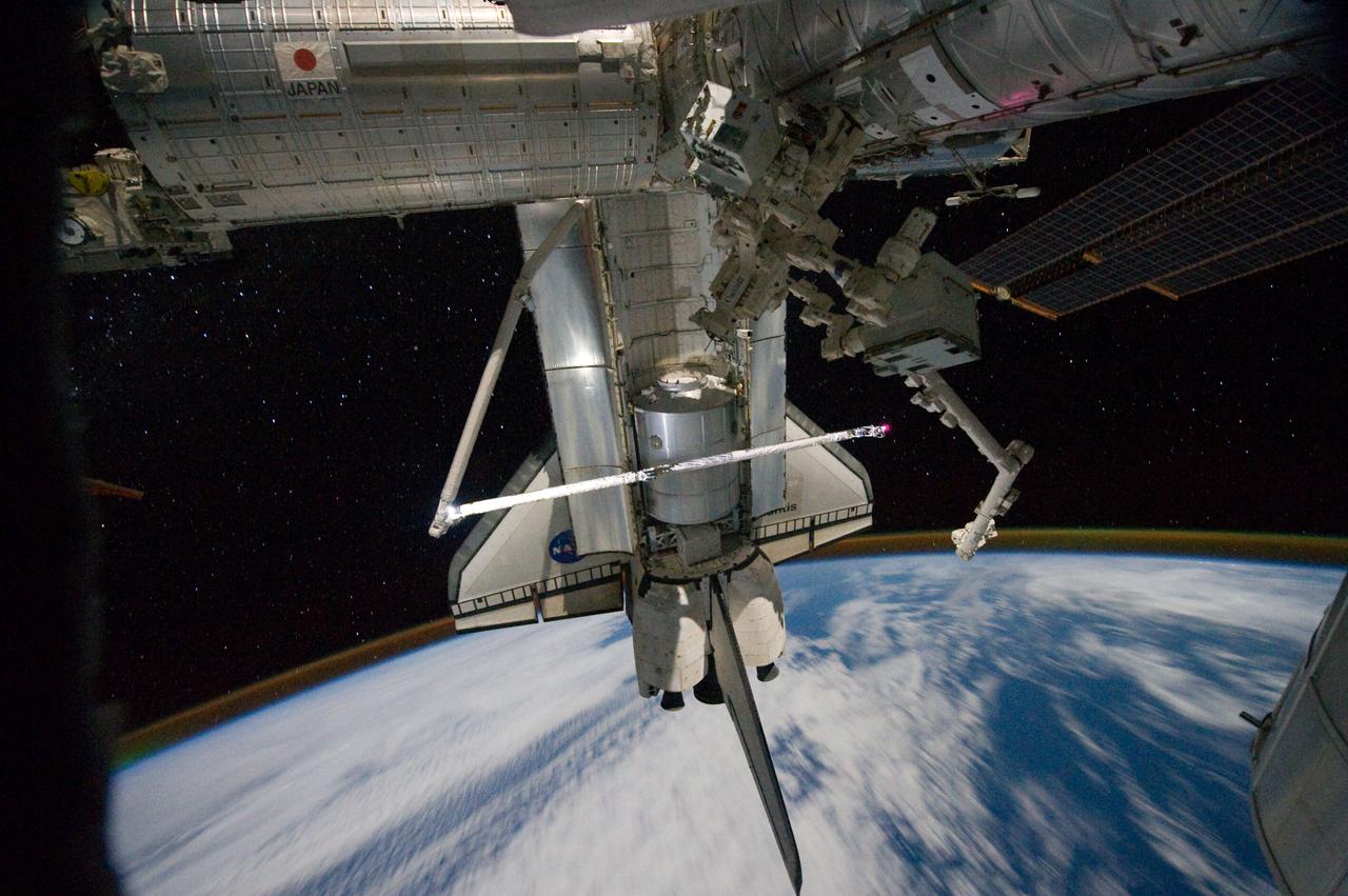 ISS028-E-017801 (18 July 2011) --- This view of the space shuttle Atlantis while still docked with the International Space Station was taken by a crew member aboard the station on the final day of joint activities between the crew members for the STS-135 and Expedition 28 missions. The robotic arm on the shuttle appears to be saluting "good-bye" to the station. Earth's airglow is seen as a thin blue line above the horizon. The Raffaello multi-purpose logistics module, full of items to be returned to Earth, is seen in the aft cargo bay.