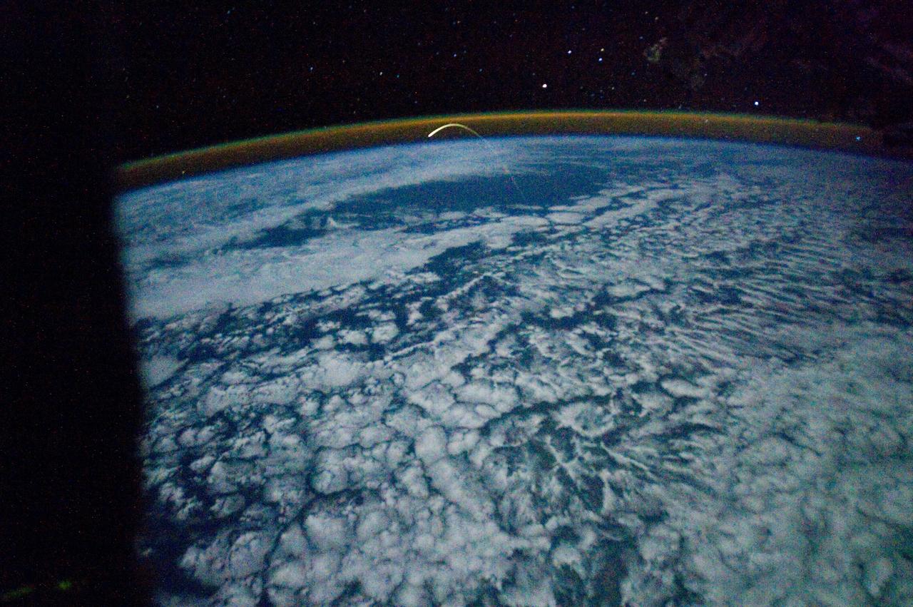 ISS028-E-018188 (21 July 2011) --- This unprecedented view of the space shuttle Atlantis, appearing like a bean sprout against clouds and city lights, on its way home, was photographed by the Expedition 28 crew of the International Space Station. Airglow over Earth can be seen in the background.
