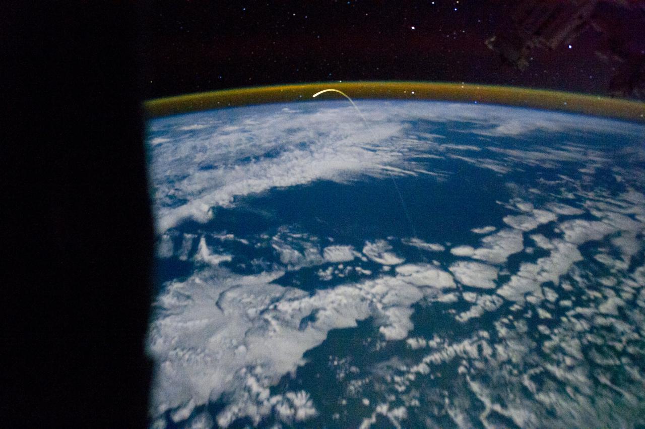 ISS028-E-018199 (21 July 2011) --- This unprecedented view of the space shuttle Atlantis, appearing like a bean sprout against clouds and city lights, on its way home, was photographed by the Expedition 28 crew of the International Space Station. Airglow over Earth can be seen in the background.