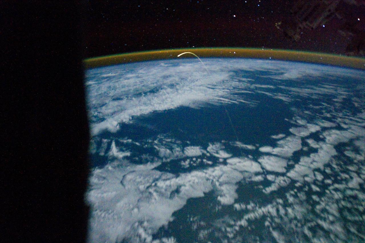 ISS028-E-018200 (21 July 2011) --- This unprecedented view of the space shuttle Atlantis, appearing like a bean sprout against clouds and city lights, on its way home, was photographed by the Expedition 28 crew of the International Space Station. Airglow over Earth can be seen in the background.