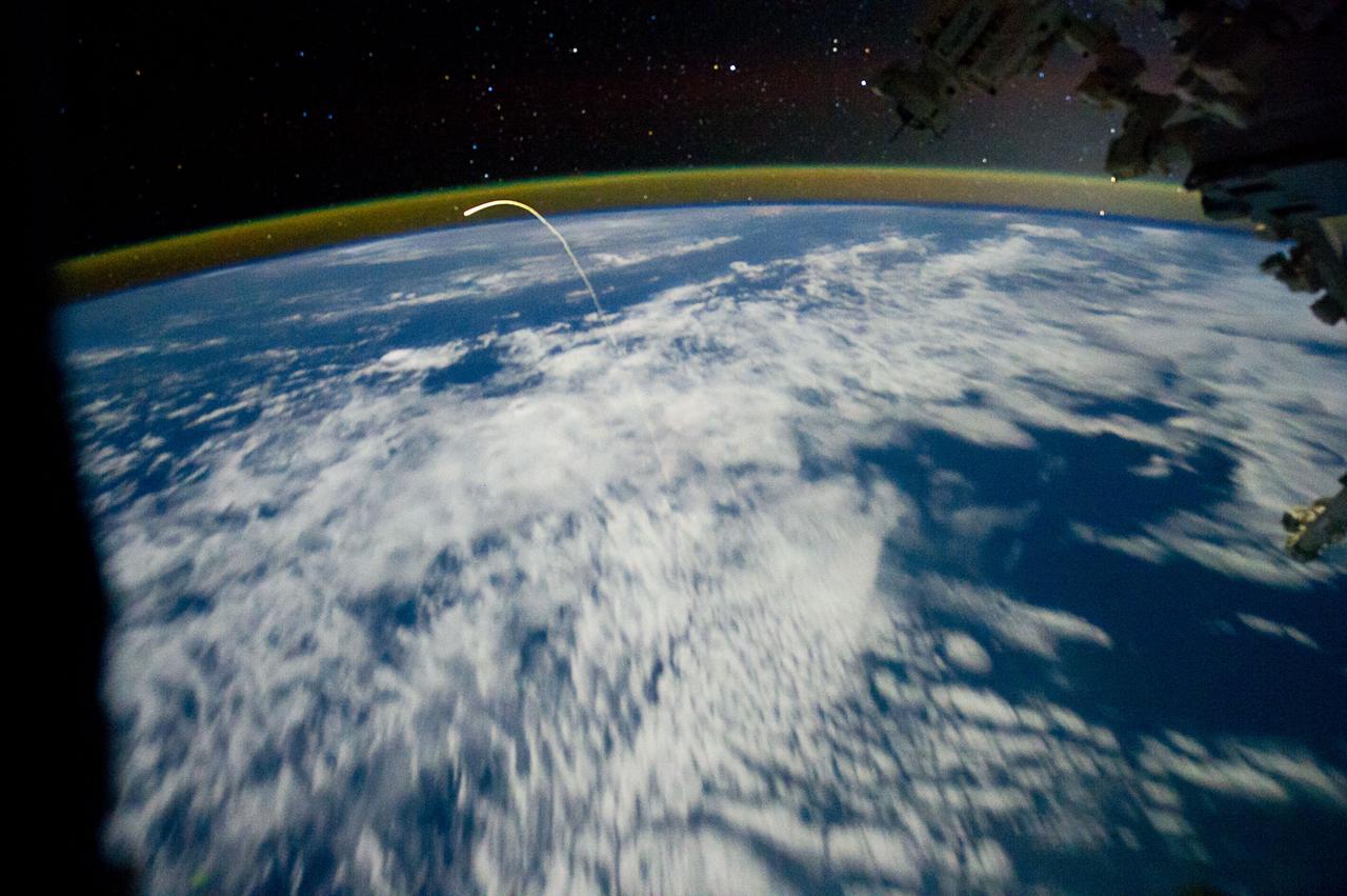 ISS028-E-018217 (21 July 2011) --- This unprecedented view of the space shuttle Atlantis, appearing like a bean sprout against clouds and city lights, on its way home, was photographed by the Expedition 28 crew on the International Space Station. Airglow over Earth can be seen in the background.