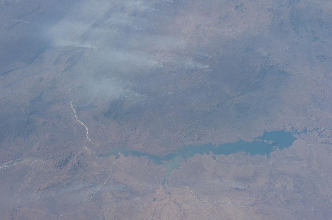 ISS028-E-018657 (23 July 2011) --? One of the Expedition 28 crew members aboard the International Space Station photographed this northward looking view featuring the reservoir of Cahora Bassa in extreme western Mozambique, formed by damming the Zambezi River. Also visible are numerous plumes from fires in the wooded plateau region north of the lake on the Mozambique-Zambia frontier.