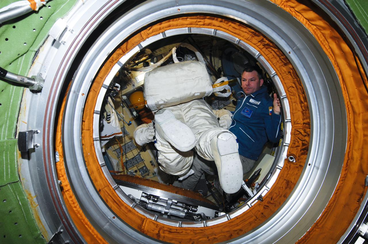 ISS028-E-019437 (29 July 2011) --- Russian cosmonaut Alexander Samokutyaev, Expedition 28 flight engineer, works with Russian Orlan-MK spacesuits in the Pirs Docking Compartment of the International Space Station in preparation for a spacewalk scheduled for Aug. 3, 2011. During the six-hour excursion Samokutyaev and Russian cosmonaut Sergei Volkov (out of frame), flight engineer, will move a cargo boom from one airlock to another, install a prototype laser communications system and deploy an amateur radio micro-satellite.