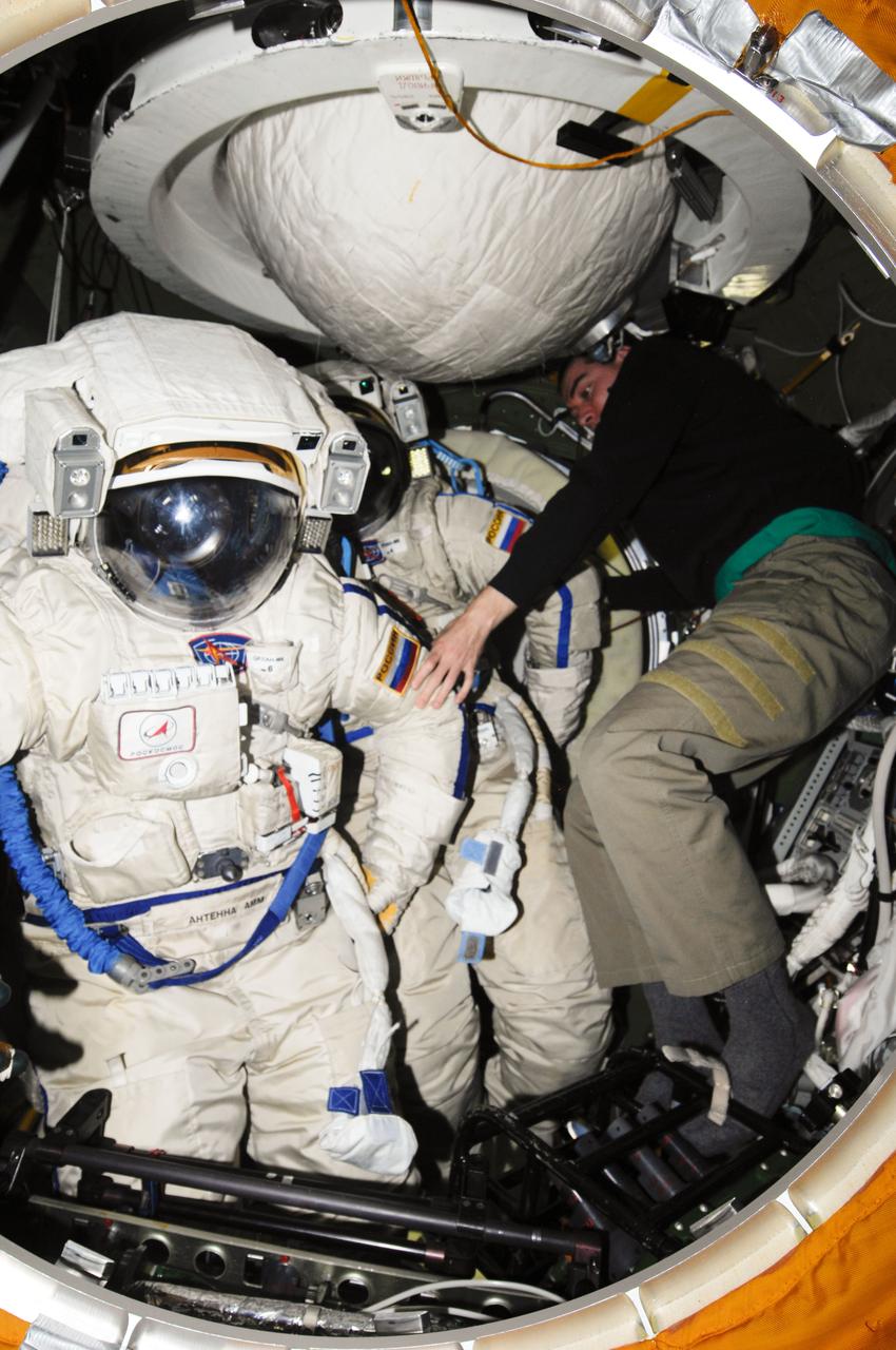 ISS028-E-019440 (29 July 2011) --- Russian cosmonaut Sergei Volkov, Expedition 28 flight engineer, works with Russian Orlan-MK spacesuits in the Pirs Docking Compartment of the International Space Station in preparation for a spacewalk scheduled for Aug. 3, 2011. During the six-hour excursion Volkov and Russian cosmonaut Alexander Samokutyaev (out of frame), flight engineer, will move a cargo boom from one airlock to another, install a prototype laser communications system and deploy an amateur radio micro-satellite.