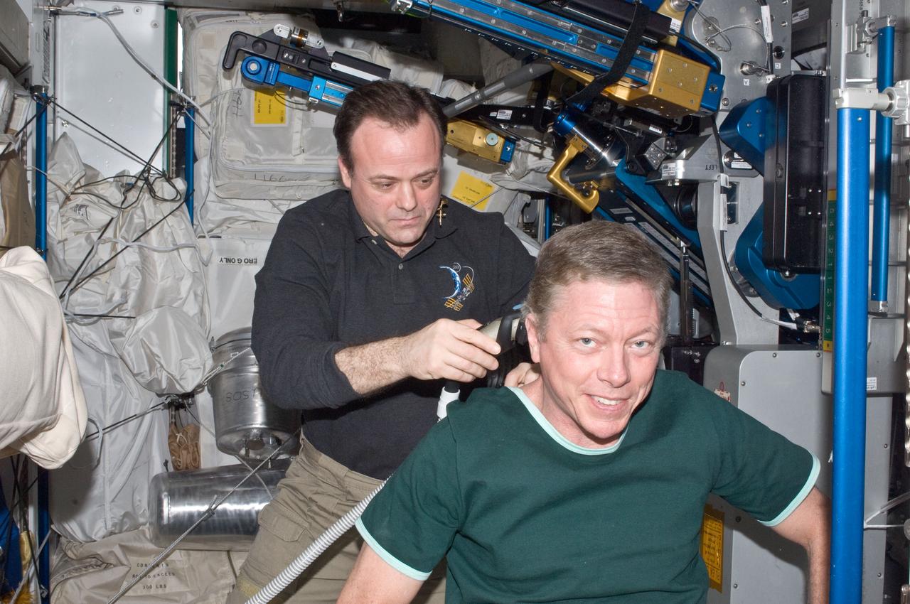 ISS028-E-019487 (31 July 2011) --- NASA astronaut Ron Garan, Expedition 28 flight engineer, trims astronaut Mike Fossum?s hair in the Tranquility node of the International Space Station. Garan used hair clippers fashioned with a vacuum device to garner freshly cut hair.