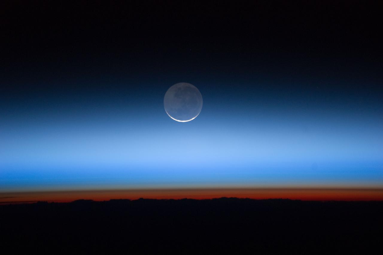 ISS028-E-020073 (31 July 2011) --- Photographed by an Expedition 28  crew member onboard the International Space Station,  this image shows the moon at center, with the limb of  Earth near the bottom transitioning into the orange-colored troposphere, the lowest and most dense portion of the Earth's atmosphere. The troposphere ends abruptly at the tropopause, which appears in the image as the sharp boundary between the orange- and blue- colored atmosphere. The silvery-blue noctilucent clouds extend far above the Earth's troposphere.