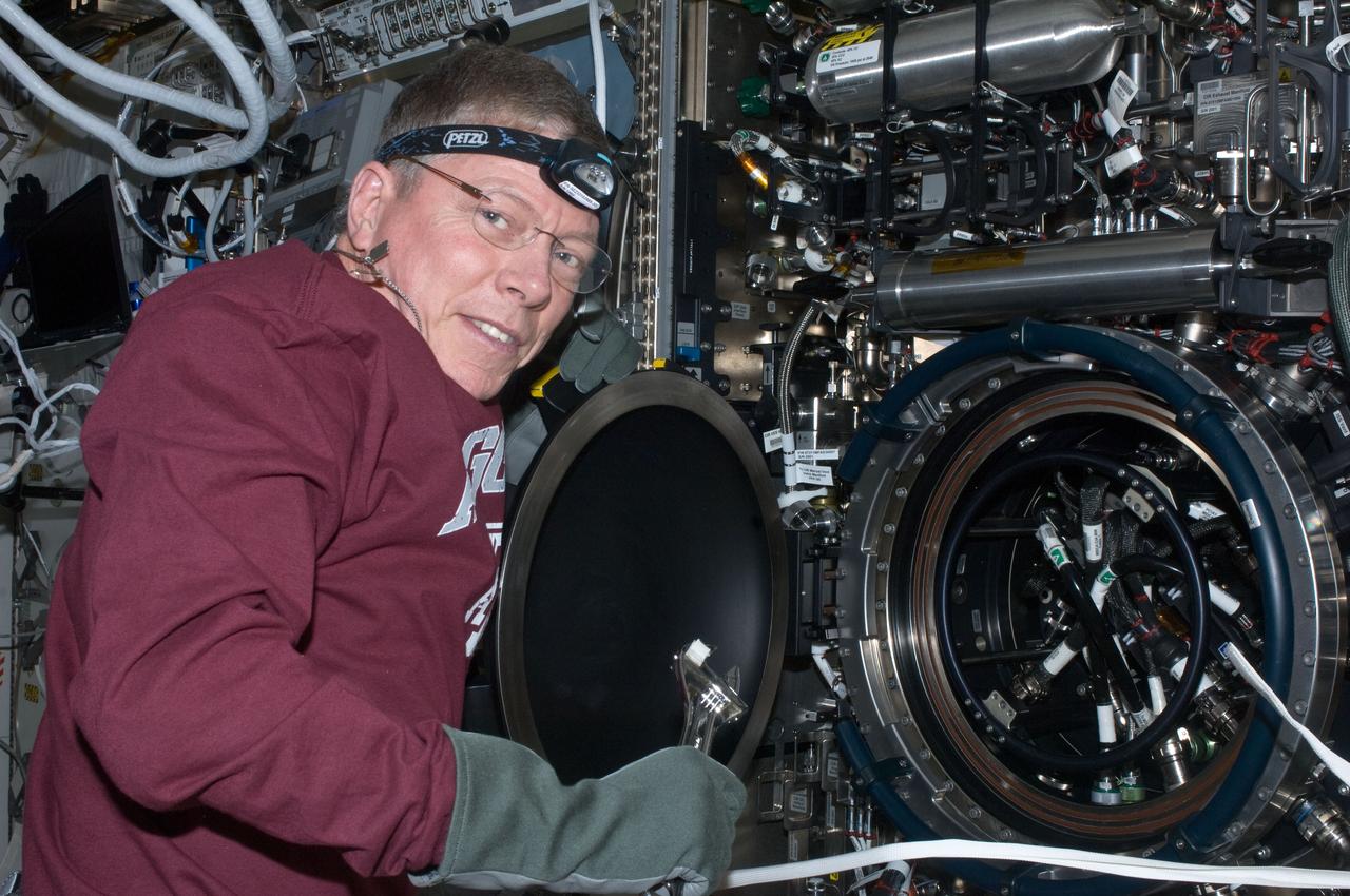 ISS028-E-020221 (1 Aug. 2011) --- NASA astronaut Mike Fossum, Expedition 28 flight engineer, services the Multi-user Drop Combustion Apparatus / Chamber Insert Assembly (MDCA CIA) in the Destiny laboratory of the International Space Station.