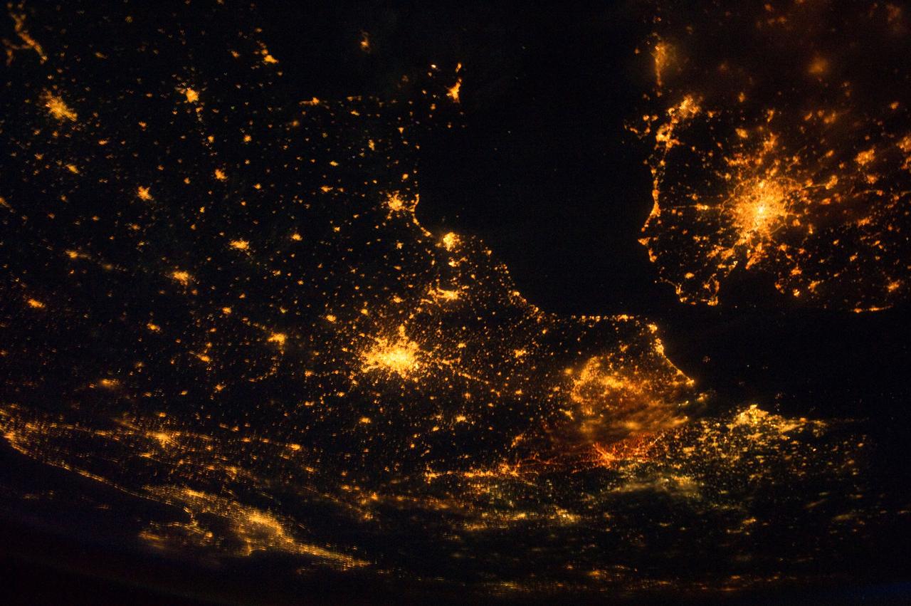 ISS028-E-024360 (10 Aug. 2011) --- This night time view of northwestern Europe is featured in this image photographed by an Expedition 28 crew member on the International Space Station. Several of the oldest cities of northwestern Europe are highlighted in this photograph taken at 00:25:26 Greenwich Mean Time (GMT). While the landscape is dotted with numerous clusters of lights from individual urban areas, the metropolitan areas of London (United Kingdom), Paris (France), Brussels (Belgium) and Amsterdam (Netherlands) stand out due to their large light ?footprints?. The metropolitan area of Milan, Italy is also visible at lower left. This photograph was taken with a short camera lens, providing the large field of view recorded in the image. To give a sense of scale, the centers of the London and Paris metropolitan areas are approximately 340 kilometers distant from each other. The image is also oblique, or taken while looking outward at an angle from the station; this tends to foreshorten the image, making the distance between Paris and Milan (approximately 640 kilometers) appear less than that of Paris to London. In contrast to the land surface defined by the city lights, the English Channel at right presents a uniform dark appearance. Similarly, the Alps (bottom center) to the north of Milan are also largely devoid of lights. While much of the atmosphere was clear at the time the image was taken, the lights of the Brussels metropolitan area are dimmed by thin cloud cover.
