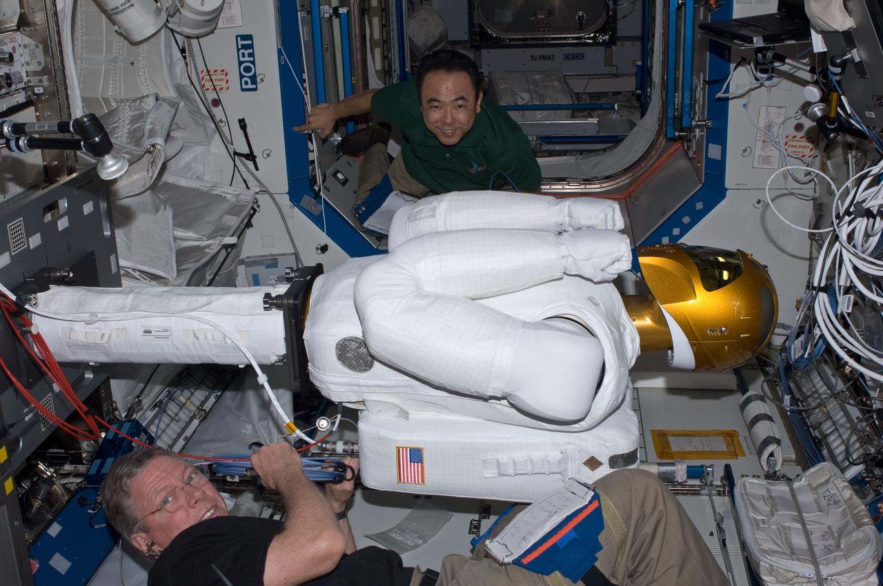 ISS028-E-030093 (22 Aug. 2011) --- NASA astronaut Mike Fossum (bottom) and Japan Aerospace Exploration Agency astronaut Satoshi Furukawa, both Expedition 28 flight engineers, make preparations to power-up Robonaut 2 ? the first dexterous humanoid robot in space ? in the Destiny laboratory of the International Space Station.