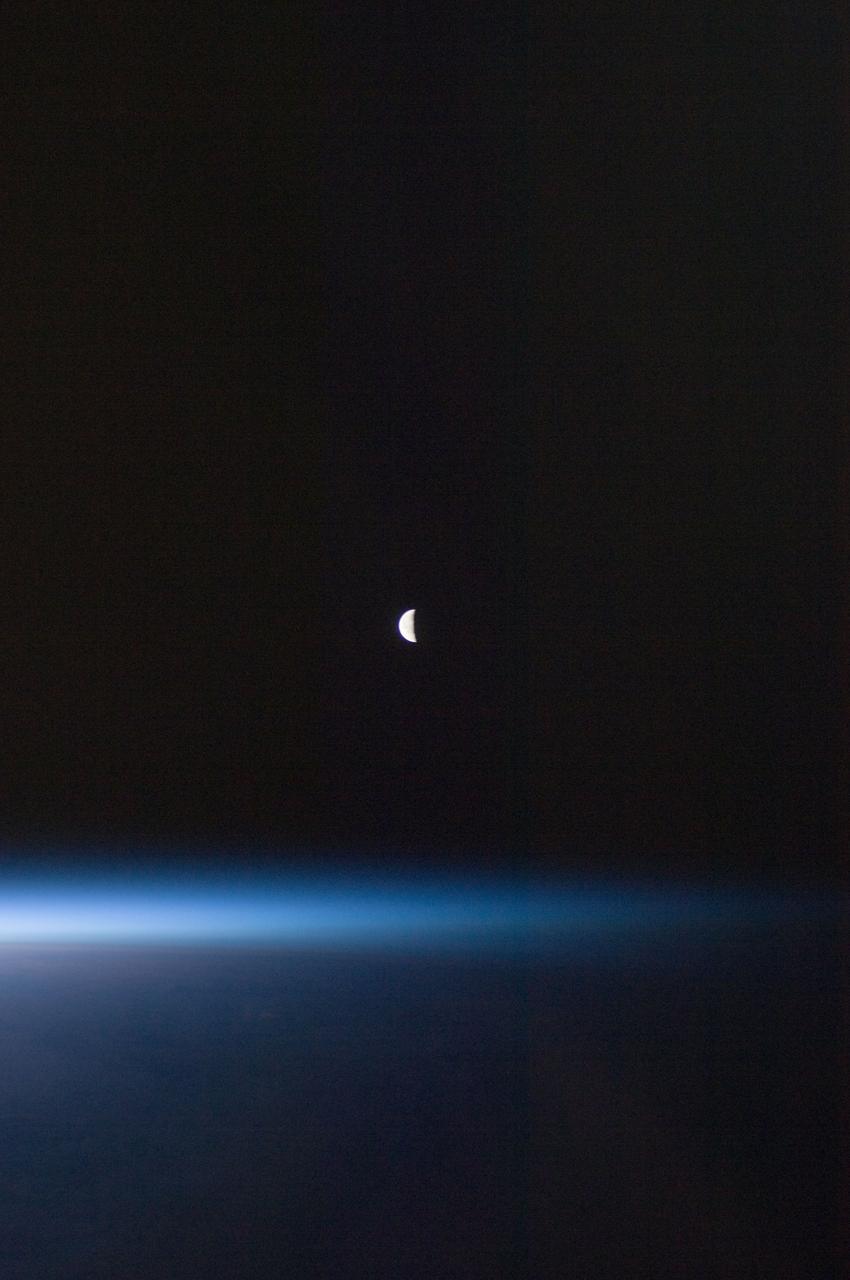 ISS028-E-030097 (22 Aug. 2011) --- A last quarter moon appears at the center of this night time photo taken from the International   Space Station in Earth orbit. A thin line of the planet's atmosphere is the other illuminated object in the picture.