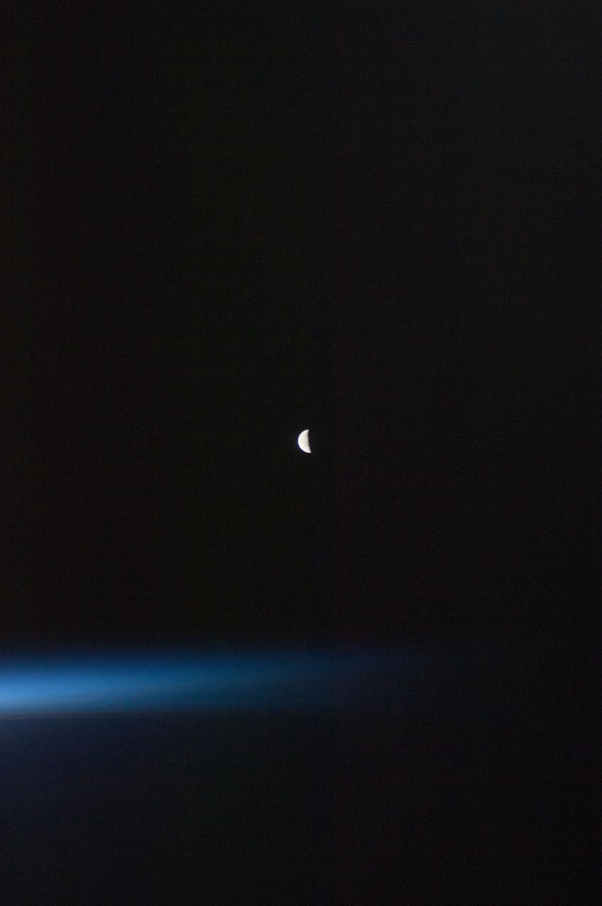 ISS028-E-030098 (22 Aug. 2011) --- A last quarter moon appears at the center of this night time photo taken from the International   Space Station in Earth orbit. A thin line of the planet's atmosphere is the other illuminated object in the picture.