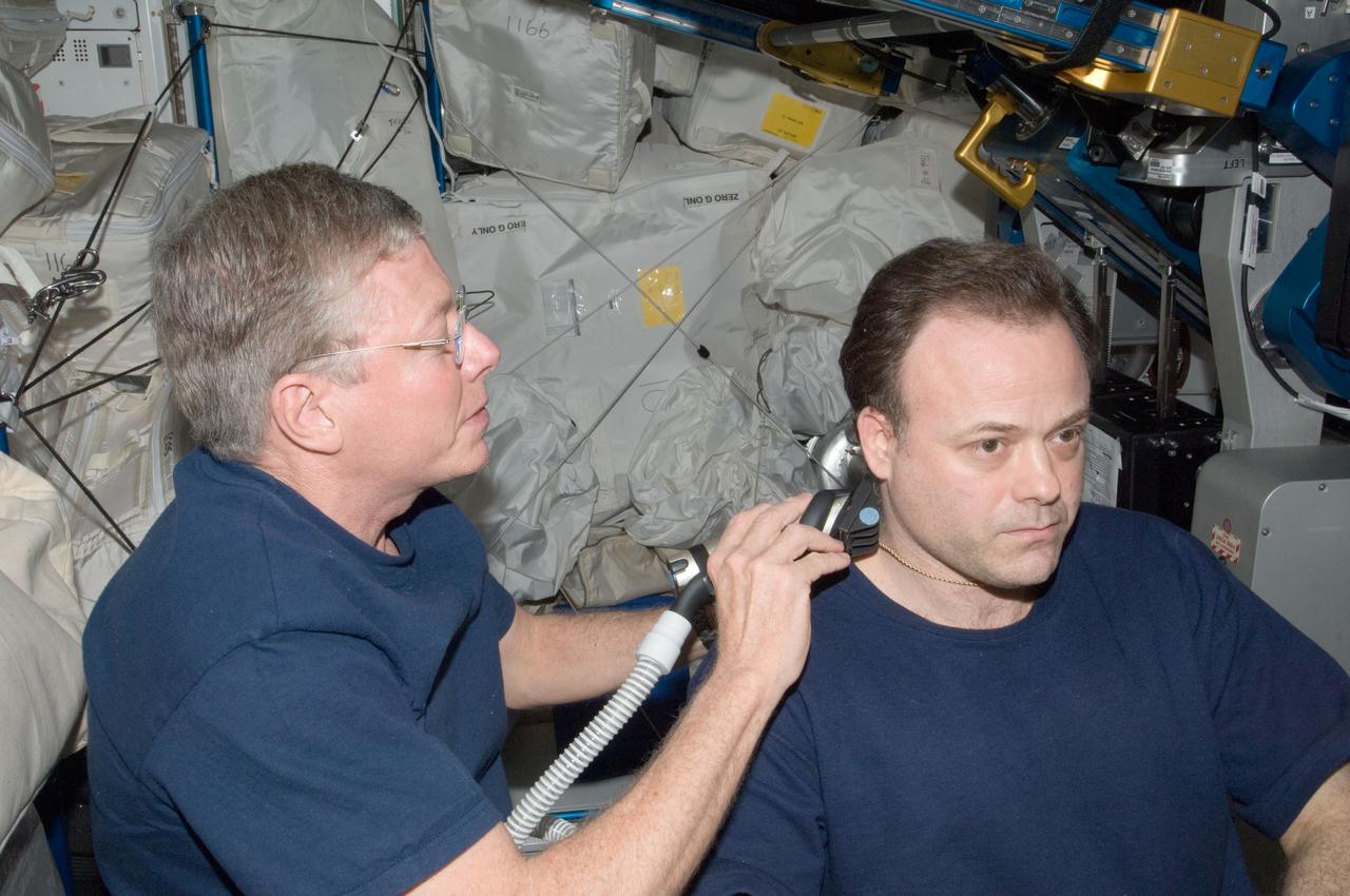 ISS028-E-035028 (27 Aug. 2011) --- NASA astronaut Mike Fossum, Expedition 28 flight engineer, trims astronaut Ron Garan's hair in the Tranquility node of the International Space Station. Fossum used hair clippers fashioned with a vacuum device to garner freshly cut hair.