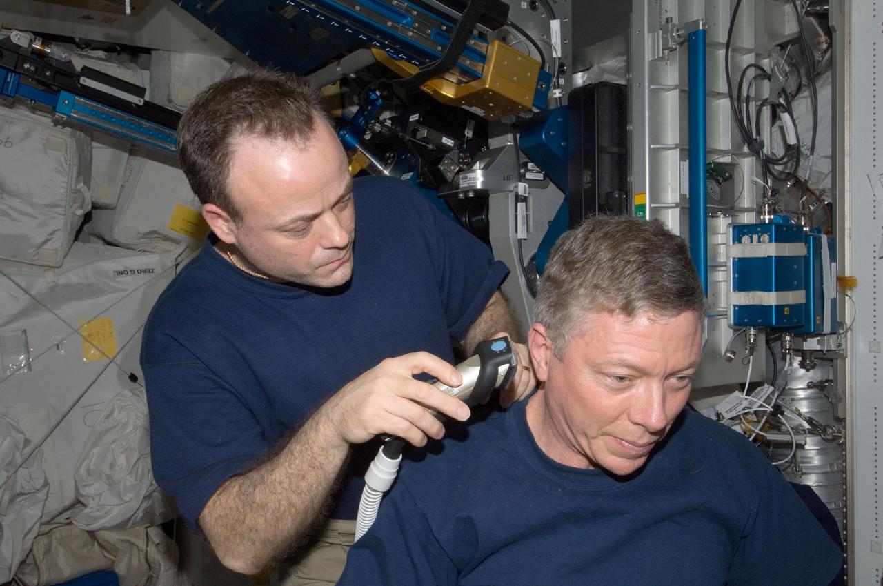 ISS028-E-035053 (27 Aug. 2011) --- NASA astronaut Ron Garan, Expedition 28 flight engineer, trims astronaut Mike Fossum's hair in the Tranquility node of the International Space Station. Garan used hair clippers fashioned with a vacuum device to garner freshly cut hair.