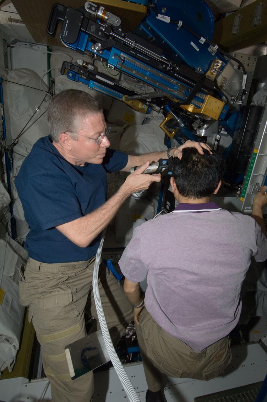 ISS028-E-035073 (27 Aug. 2011) --- NASA astronaut Mike Fossum, Expedition 28 flight engineer, trims the hair of Japan Aerospace Exploration Agency astronaut Satoshi Furukawa in the Tranquility node of the International Space Station. Fossum used hair clippers fashioned with a vacuum device to garner freshly cut hair.