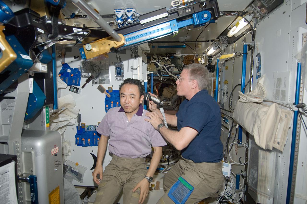 ISS028-E-035074 (27 Aug. 2011) --- NASA astronaut Mike Fossum, Expedition 28 flight engineer, trims the hair of Japan Aerospace Exploration Agency astronaut Satoshi Furukawa in the Tranquility node of the International Space Station. Fossum used hair clippers fashioned with a vacuum device to garner freshly cut hair.