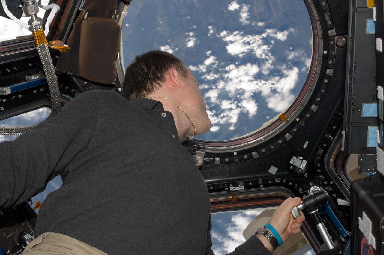 ISS028-E-048060 (11 Sept. 2011) --- NASA astronaut Ron Garan, Expedition 28 flight engineer, views a point on Earth through one of the windows in the Cupola of the International Space Station.