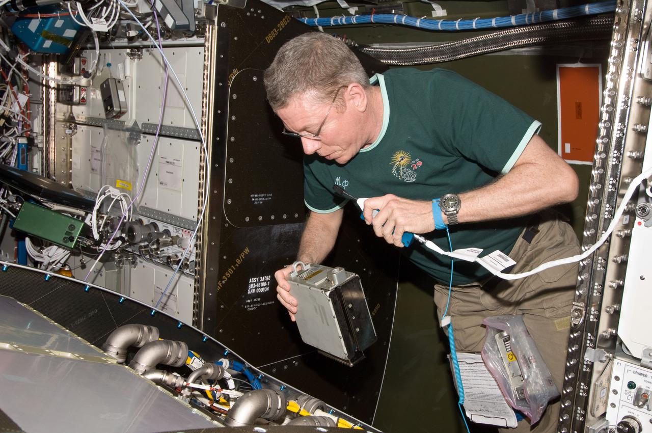 ISS029-E-029720 (17 Oct. 2011) --- NASA astronaut Mike Fossum, Expedition 29 commander, uses a communication system while performing in-flight maintenance (IFM) of removing and replacing the failed Remote Power Controller Module (RPCM) equipment in the Destiny laboratory of the International Space Station.