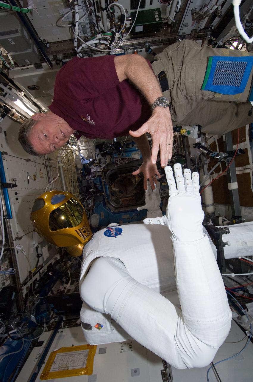 ISS029-E-039212 (4 Nov. 2011) --- NASA astronaut Mike Fossum, Expedition 29 commander, works with Robonaut 2 in the Destiny laboratory of the International Space Station. Fossum and Japan Aerospace Exploration Agency astronaut Satoshi Furukawa (out of frame), flight engineer, spent several hours in Destiny checking out and operating R2.