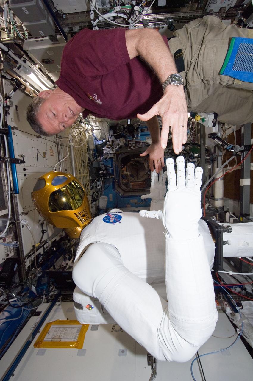ISS029-E-039213 (4 Nov. 2011) --- NASA astronaut Mike Fossum, Expedition 29 commander, works with Robonaut 2 in the Destiny laboratory of the International Space Station. Fossum and Japan Aerospace Exploration Agency astronaut Satoshi Furukawa (out of frame), flight engineer, spent several hours in Destiny checking out and operating R2.