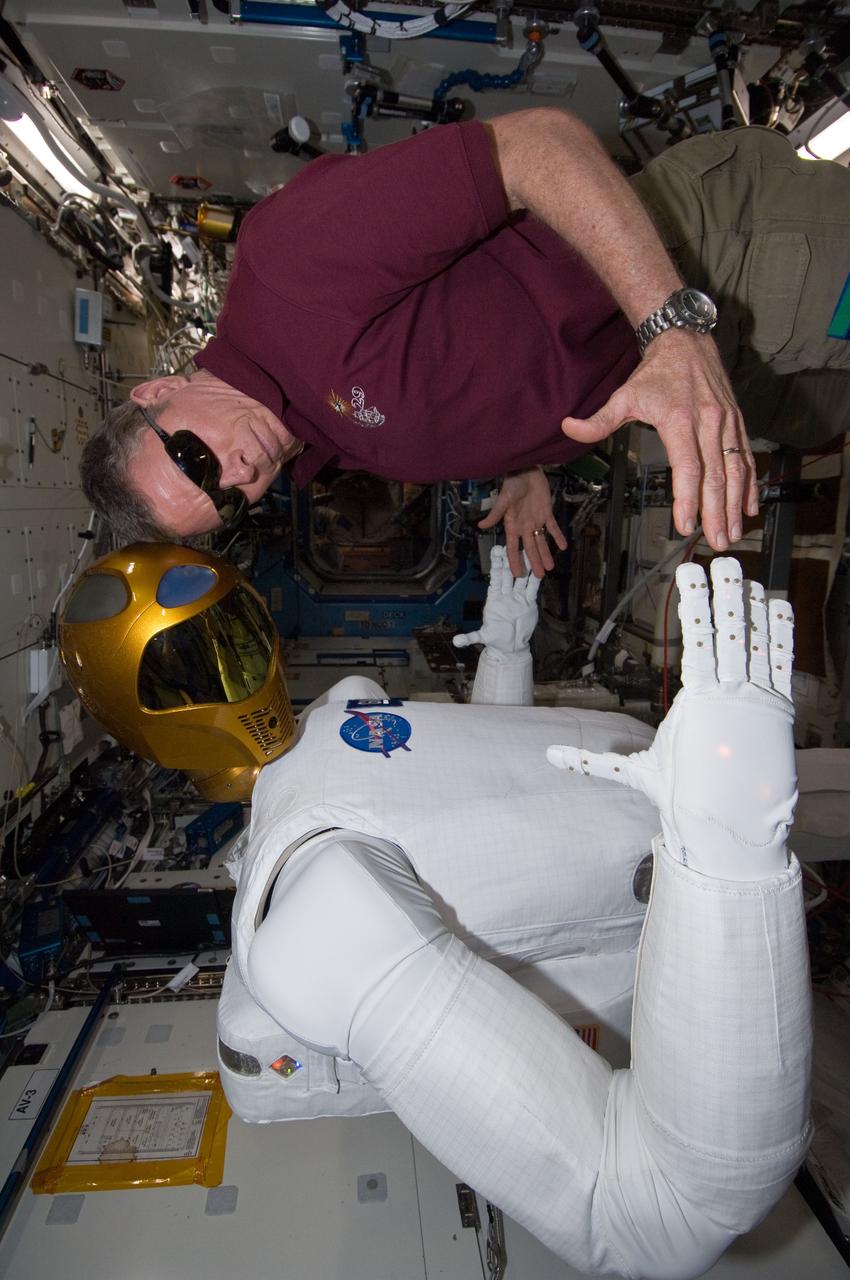 ISS029-E-039218 (4 Nov. 2011) --- NASA astronaut Mike Fossum, Expedition 29 commander, works with Robonaut 2 in the Destiny laboratory of the International Space Station. Fossum and Japan Aerospace Exploration Agency astronaut Satoshi Furukawa (out of frame), flight engineer, spent several hours in Destiny checking out and operating R2.