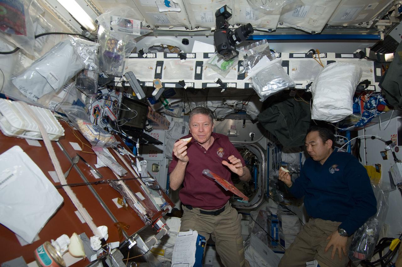 ISS029-E-040705 (8 Nov. 2011) --- NASA astronaut Mike Fossum (left), Expedition 29 commander; and Japan Aerospace Exploration Agency astronaut Satoshi Furukawa, flight engineer, enjoy a snack in the Unity node of the International Space Station.