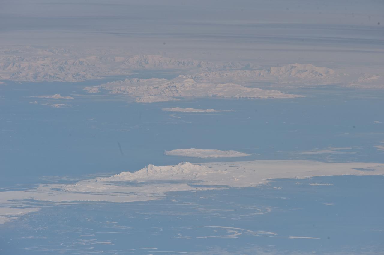 ISS029-E-041836 (4 Oct. 2011) --- South Shetland Islands and Antarctic Peninsula are featured in this image photographed by an Expedition 29 crew member on the International Space Station (ISS). The inclined equatorial orbit of the space station limits nadir Earth views?looking ?straight down? at the surface from the spacecraft?to latitudes between approximately 52 North and 52 South. When viewing conditions are ideal, the crew can obtain detailed oblique imagery?looking outwards at an angle from the space station?of regions at higher latitudes such as Greenland or, in this image, Antarctica. While the bulk of the continent of Antarctica is currently situated over the South Pole, the narrow Antarctic Peninsula extends like a finger towards the southern tip of South America. The northernmost part of the Peninsula is known as Graham Land, a small portion of which (located at approximately 64 South latitude) can be seen at top left in this photograph. Two of the South Shetland Islands that lay off the coast of Graham Land to the north-northwest, Livingston Island and Deception Island, are visible in the image. While both islands have a volcanic origin, active volcanism at Deception Island has been recorded since 1800; the last verified eruptive activity occurred in 1970. Closer to the coastline of Graham Land, Brabant Island (not considered to be part of the South Shetlands) also includes numerous outcrops of volcanic rock attesting to the complex tectonic history of the region. The space station was located over the South Atlantic Ocean, approximately 1,800 kilometers to the northeast in terms of its ground track, when this image was taken. This long viewing distance, combined with the highly oblique viewing angle, accentuates shadowing of the ground surface and provides a sense of the topography similar to the view one gets from an airplane. It also causes foreshortening of features visible in the image, making them appear closer to each other than they actually are ? for example, the actual distance between Livingston and Deception Islands is approximately 20 kilometers.