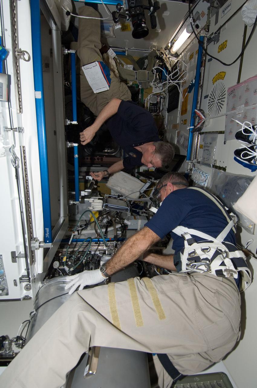ISS029-E-043420 (19 Nov. 2011) --- NASA astronauts Mike Fossum (background), Expedition 29 commander; and Dan Burbank, flight engineer, work with the Advanced Recycle Filter Tank Assembly (ARFTA) in the Tranquility node of the International Space Station.