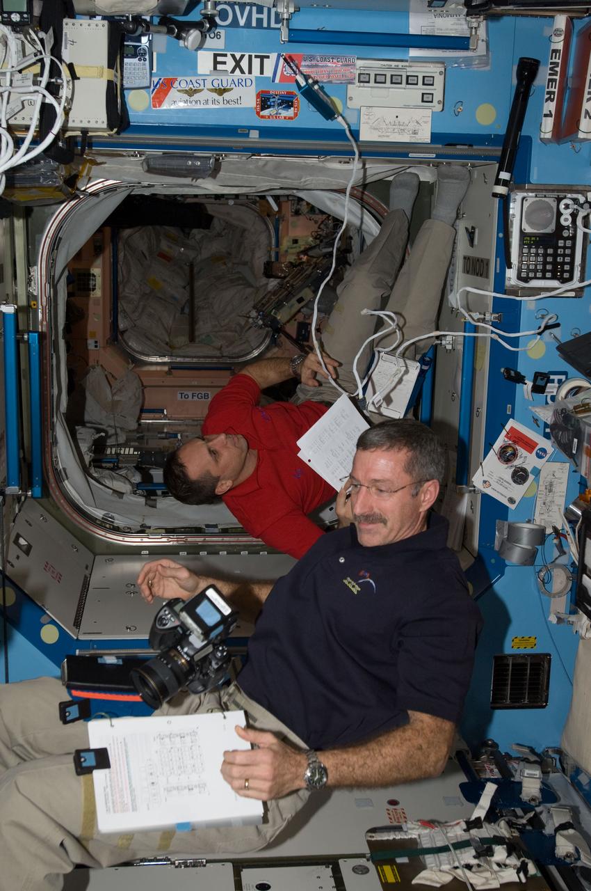 ISS030-E-007557 (3 Dec. 2011) --- NASA astronaut Dan Burbank (foreground), Expedition 30 commander; and Russian cosmonaut Anton Shkaplerov, flight engineer, work in the Destiny laboratory of the International Space Station.