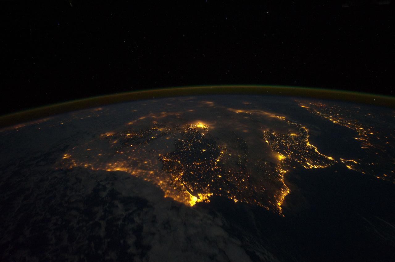 ISS030-E-010008 (4 Dec. 2011) --- One of the Expedition 30 crew members aboard the Earth-orbiting International Space Station photographed this night time scene of the Iberian Peninsula on Dec. 4, 2011. The city lights of Spain and Portugal define the peninsula. Several large metropolitan areas are visible, marked by their relatively large and brightly lit areas, such as two capital cities -- Madrid, Spain, located near the center of the peninsula?s interior, and Lisbon, Portugal, located along the southwestern coastline. Ancient Seville, visible at image right to the north of the approximately 14 kilometer-wide Strait of Gibraltar, is one of the largest cities in Spain. All together, the Principality of Andorra, the Kingdom of Spain and the Portuguese Republic total approximately 590,000 square kilometers of landmass. The peninsula is bounded by the Atlantic Ocean to the northwest, west, and southwest and the Mediterranean Sea to the east. Its northeastern boundary with the rest of continental Europe is marked by the Pyrenees mountain range.  The view is looking outwards from the orbital outpost toward the east. The network of smaller cities and towns in the interior and along the coastline attest to the large extent of human presence on the Iberian landscape. Blurring of the city lights is caused by thin cloud cover (image left and center), while the cloud tops are dimly illuminated by moonlight. Though obscured, the lights of France are visible near the horizon line at image upper left, while the lights of northern Africa are more clearly discernable at image right. The gold to green line of airglow, caused by excitation of upper atmosphere gas molecules by ultraviolet radiation, parallels the horizon line (or Earth limb).